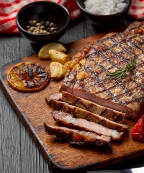 Grilled beef steak on the dark wooden background.