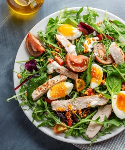 Tasty appetizing salad with turkey, eggs, bulgur and vegetables served on plate. Closeup.